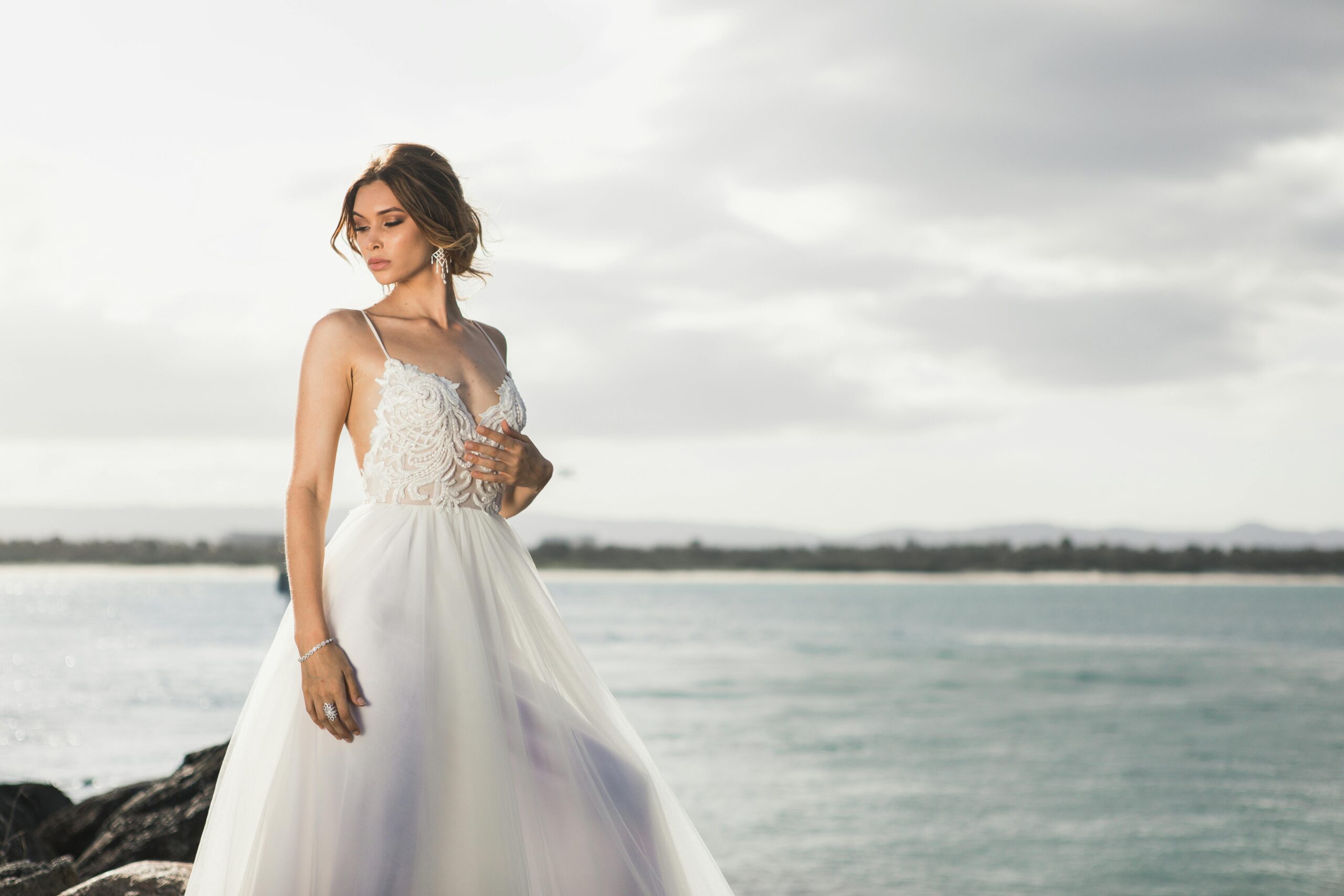 A bride fanning herself under the sun during an outdoor ceremony