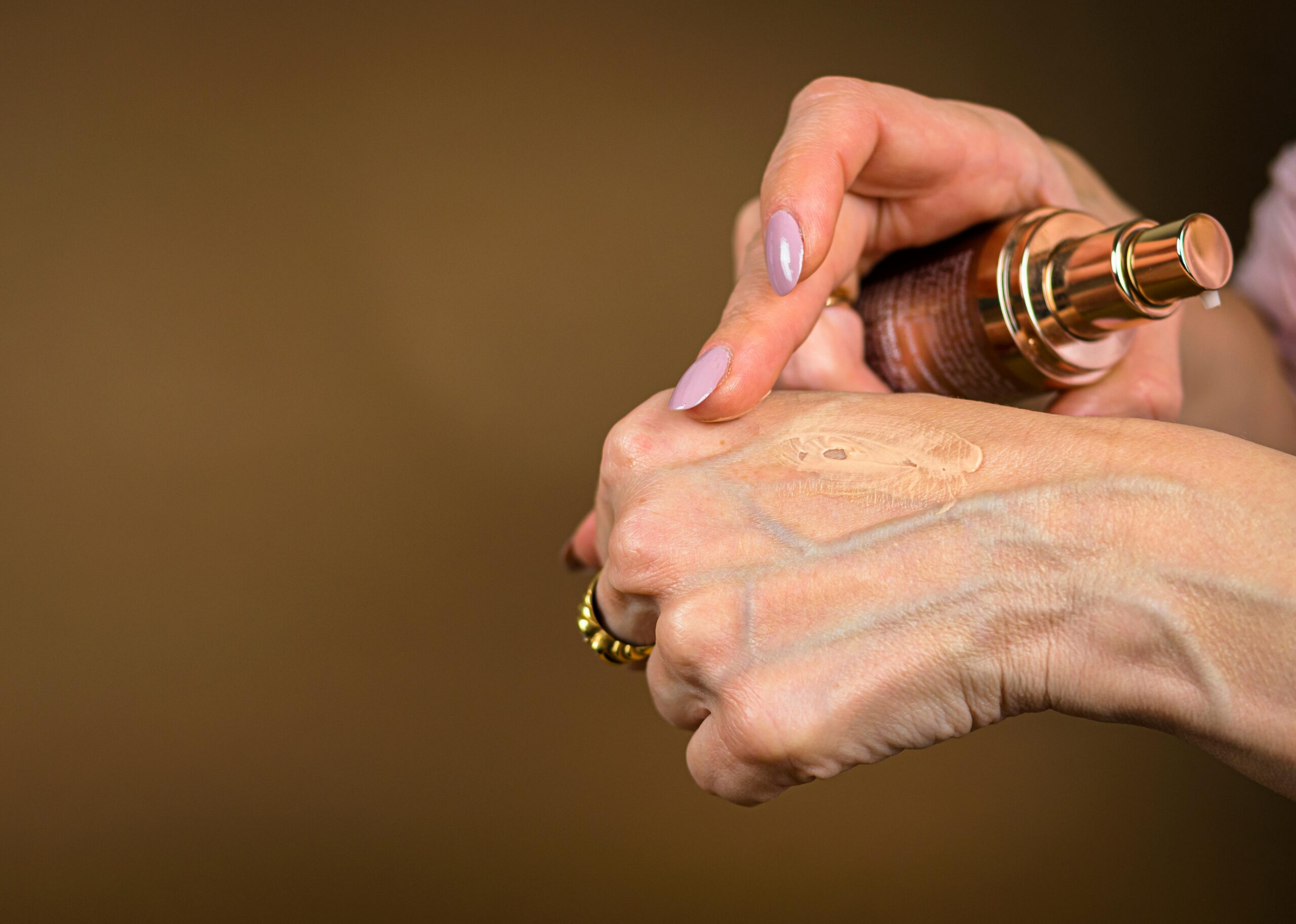 Bride applying moisturizer before makeup application