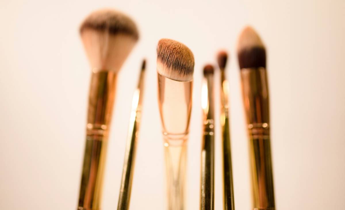 A set of luxurious makeup brushes arranged neatly on a marble countertop.