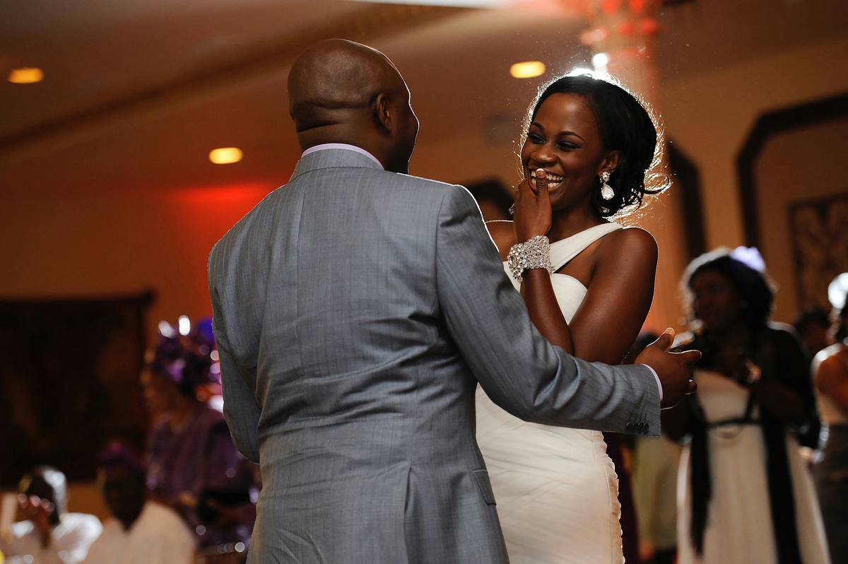 A bride wiping sweat from her forehead while dancing.