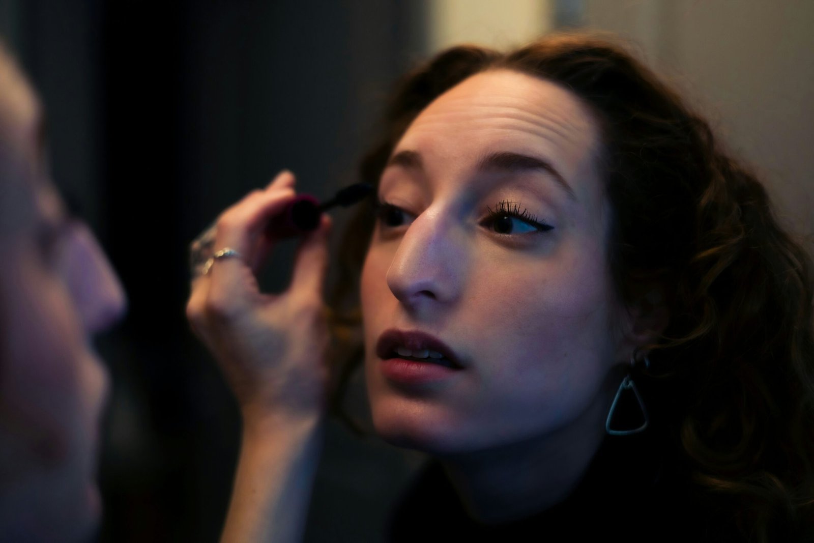 Woman applying mascara in the mirror.