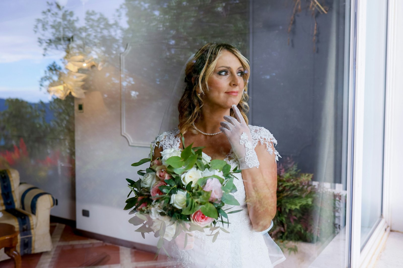 a woman standing in front of a window holding a bouquet of flowers