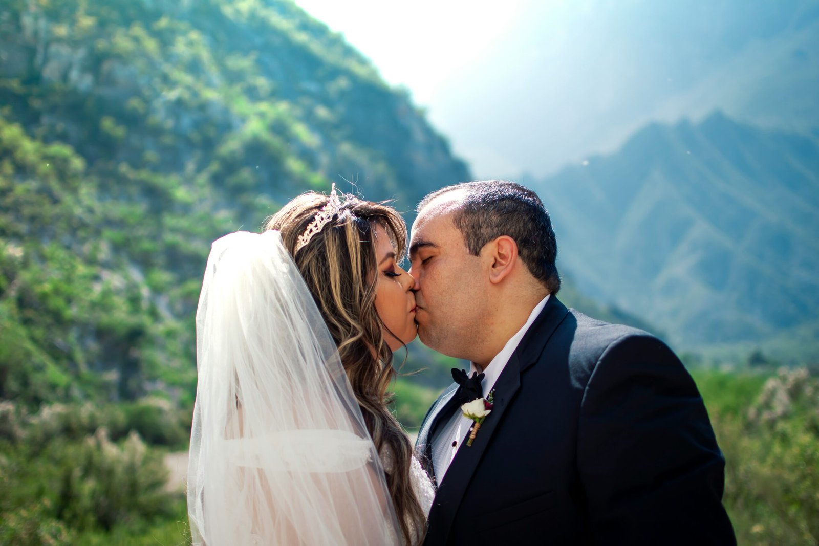 man in black suit kissing woman in white wedding dress