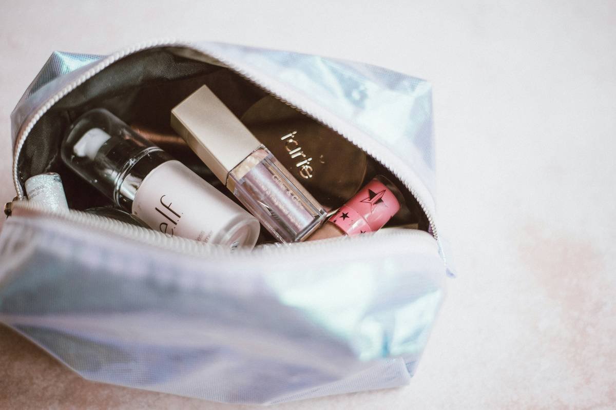 Infographic showing 7 essential items in a bridal makeup bag: setting spray, blotting papers, lipstick, concealer, powder, mini tweezers, and disposable applicators