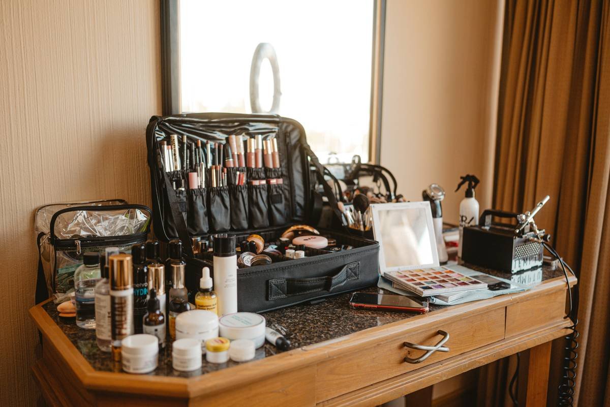 Infographic showing essential items in a wedding day makeup kit: waterproof mascara, long-wear foundation, blotting papers, setting spray, lip color, concealer, Q-tips, and micellar water wipes